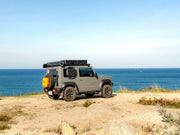 A vehicle driving on the beach, packed with gear for a camping adventure, showcasing the portability and versatility of the Compact Shelter.