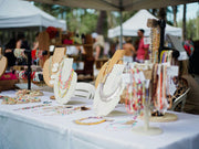 Vendor displaying handmade crafts on a table inside a 10x10 canopy tent at an outdoor market